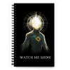 Black notebook with blue alien with a glowing head. Title says WATCH ME SHINE.